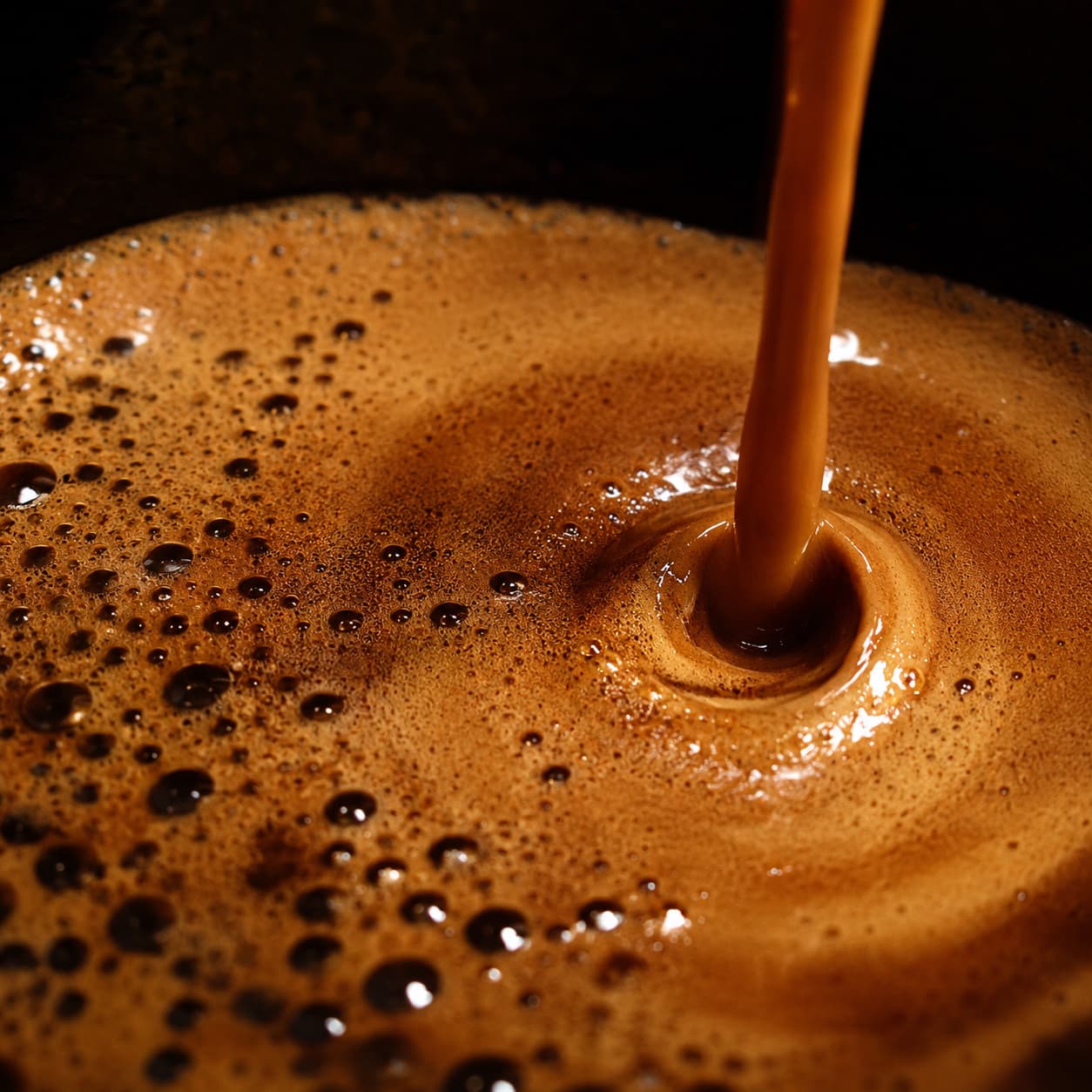 Makroaufnahme: Crema-Oberfläche im Moment des Eingießens, hartes Seitenlicht.
