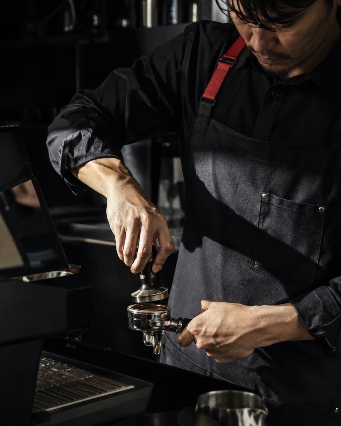 Barista beim Tampern, Handlungsfokus, kein Blick in die Kamera.